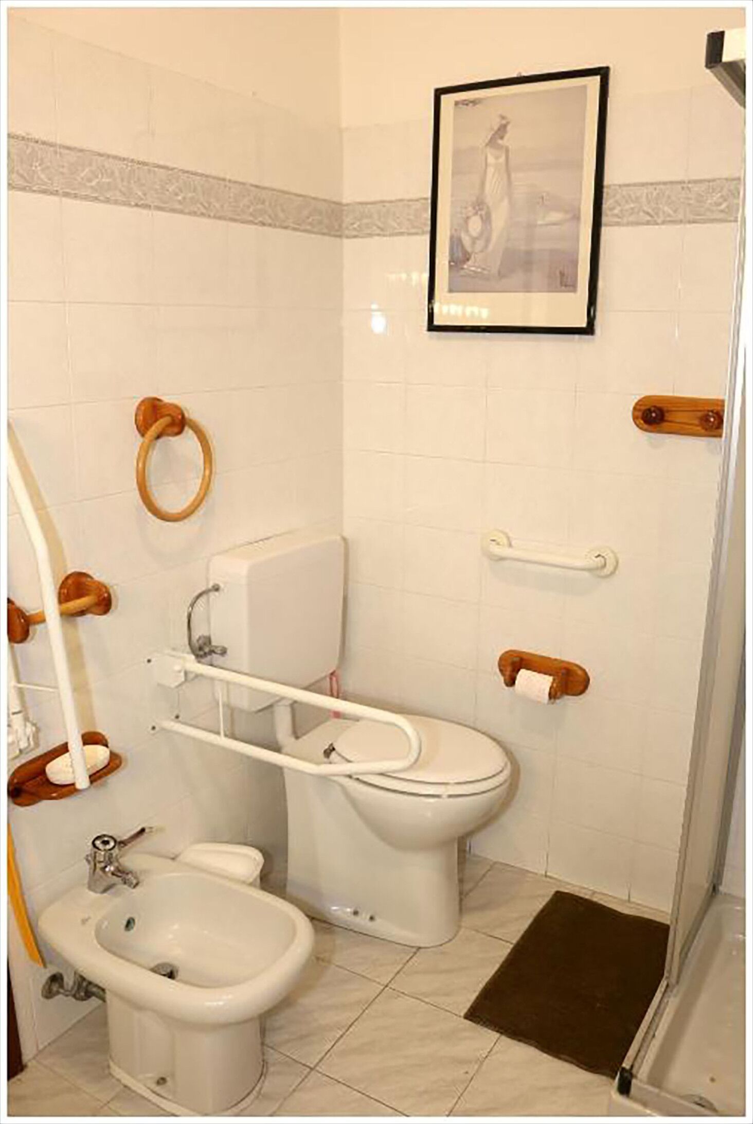 Un bagno con bidet, wc e sedile bidet. C'è un quadro appeso al muro.