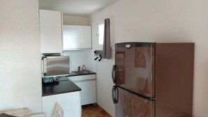 Eine kleine Küche mit Kühlschrank, Mikrowelle und Spüle.