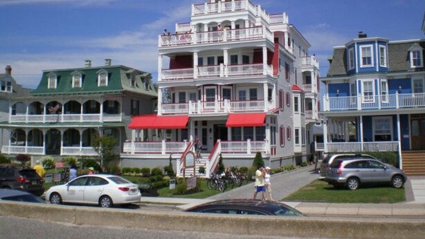 Un edificio de varios pisos con balcones y un toldo rojo.