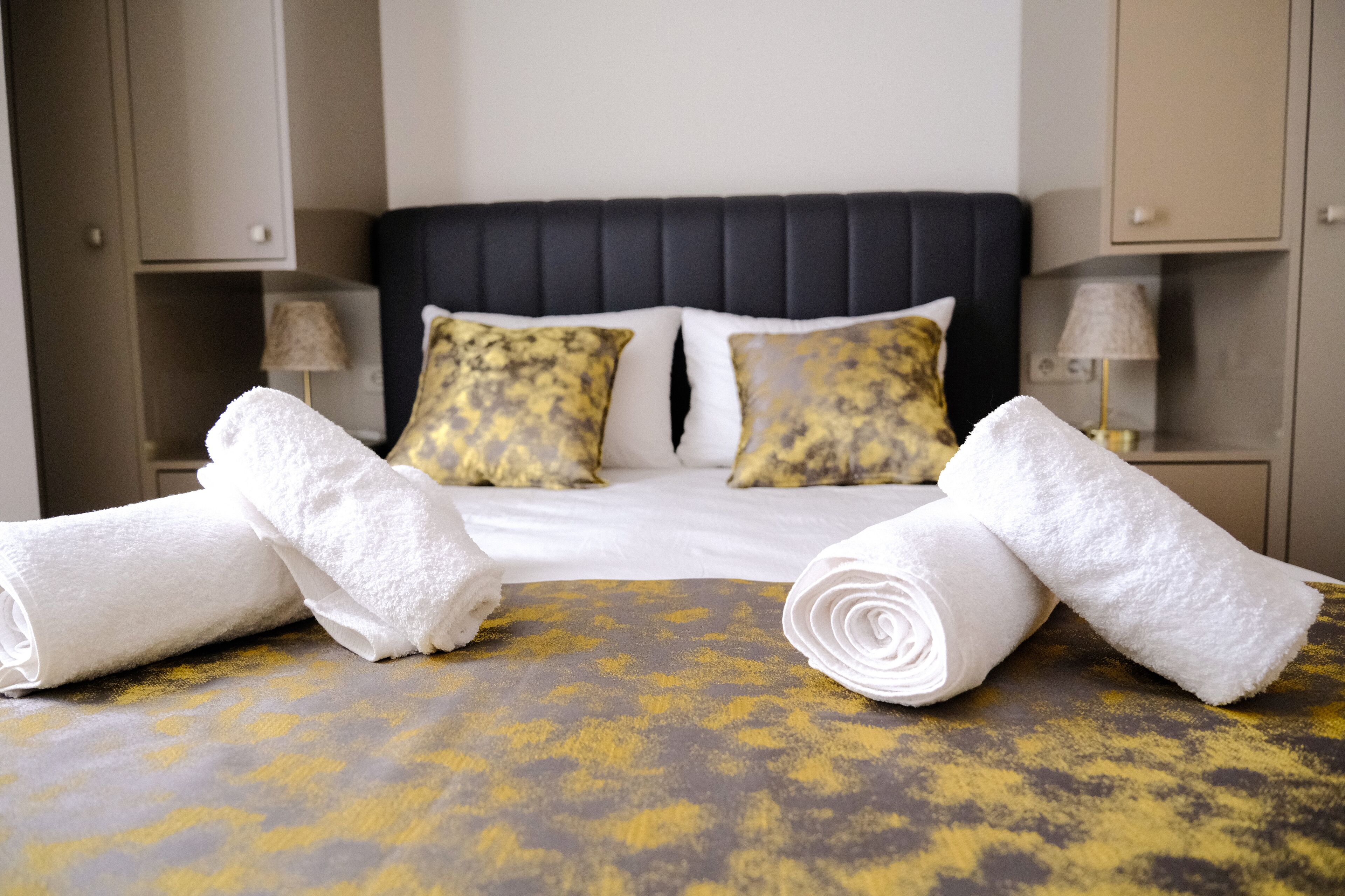 Una camera d'albergo con un letto, due cuscini, due comodini e due lampade.