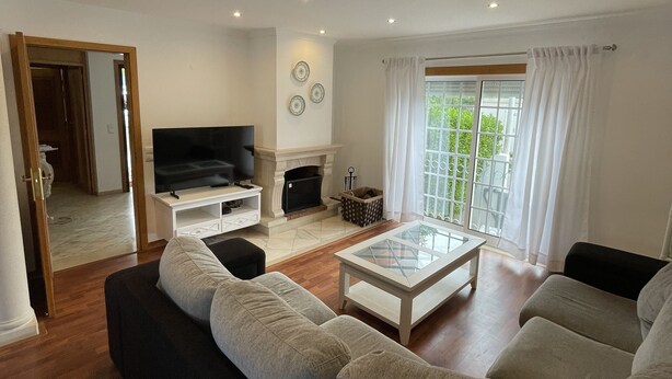 A modern living room with a sofa set, a coffee table, a fireplace, and a television. - Villa 3 Irmãos (Alvor)