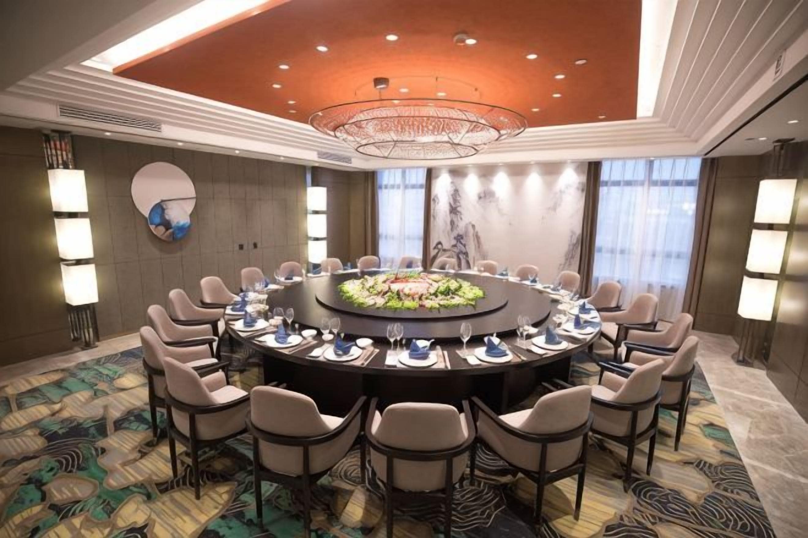 A conference room with a round table, chairs, and a chandelier.