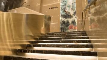 A staircase with marble steps leading up to a wall with a mural.