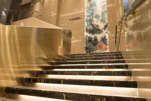 A staircase with marble steps leading up to a wall with a mural.