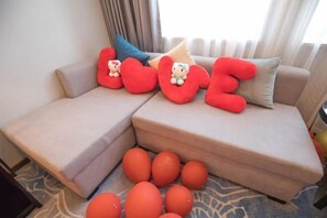 Un canapé modulable agrémenté d’un coussin en forme de cœur sur lequel est écrit le mot « AMOUR » et de peluches à l’effigie de Hello Kitty.