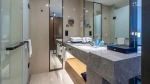 A modern bathroom with a glass shower enclosure, a large mirror, and a marble countertop.