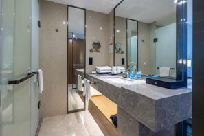 A modern bathroom with a glass shower enclosure, a large mirror, and a marble countertop.