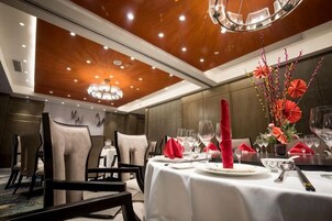 Un comedor con mesas dispuestas para una comida, sillas y una araña.