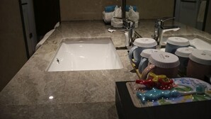 A bathroom with a sink, two faucets, and several toiletries on the counter.