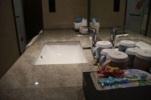 A bathroom with a sink, two faucets, and several toiletries on the counter.