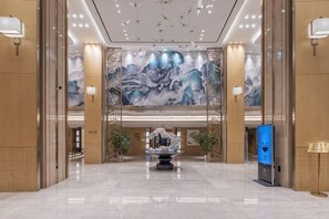 Un hall d’entrée spacieux agrémenté d’une grande fresque murale, d’un comptoir d’accueil et d’un kiosque d’information numérique.