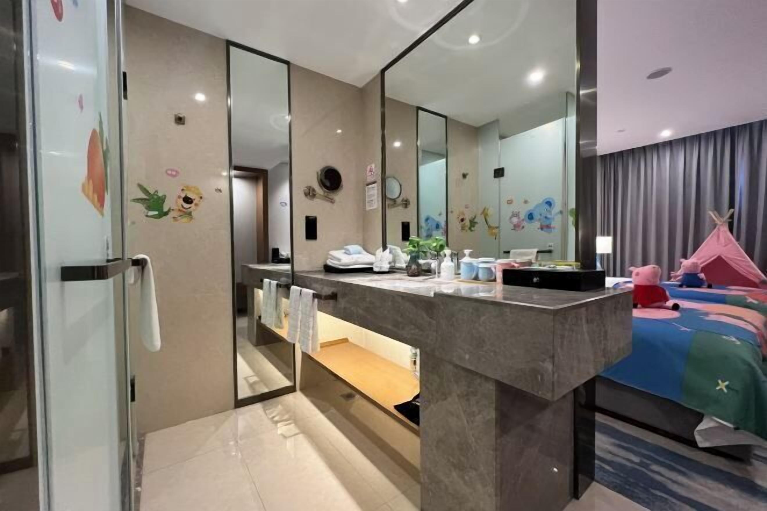 Habitación de hotel con un baño moderno, un espejo grande y una cama con ropa de cama colorida.