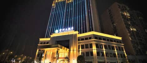 Un hotel de varios pisos con letreros iluminados y una entrada destacada.