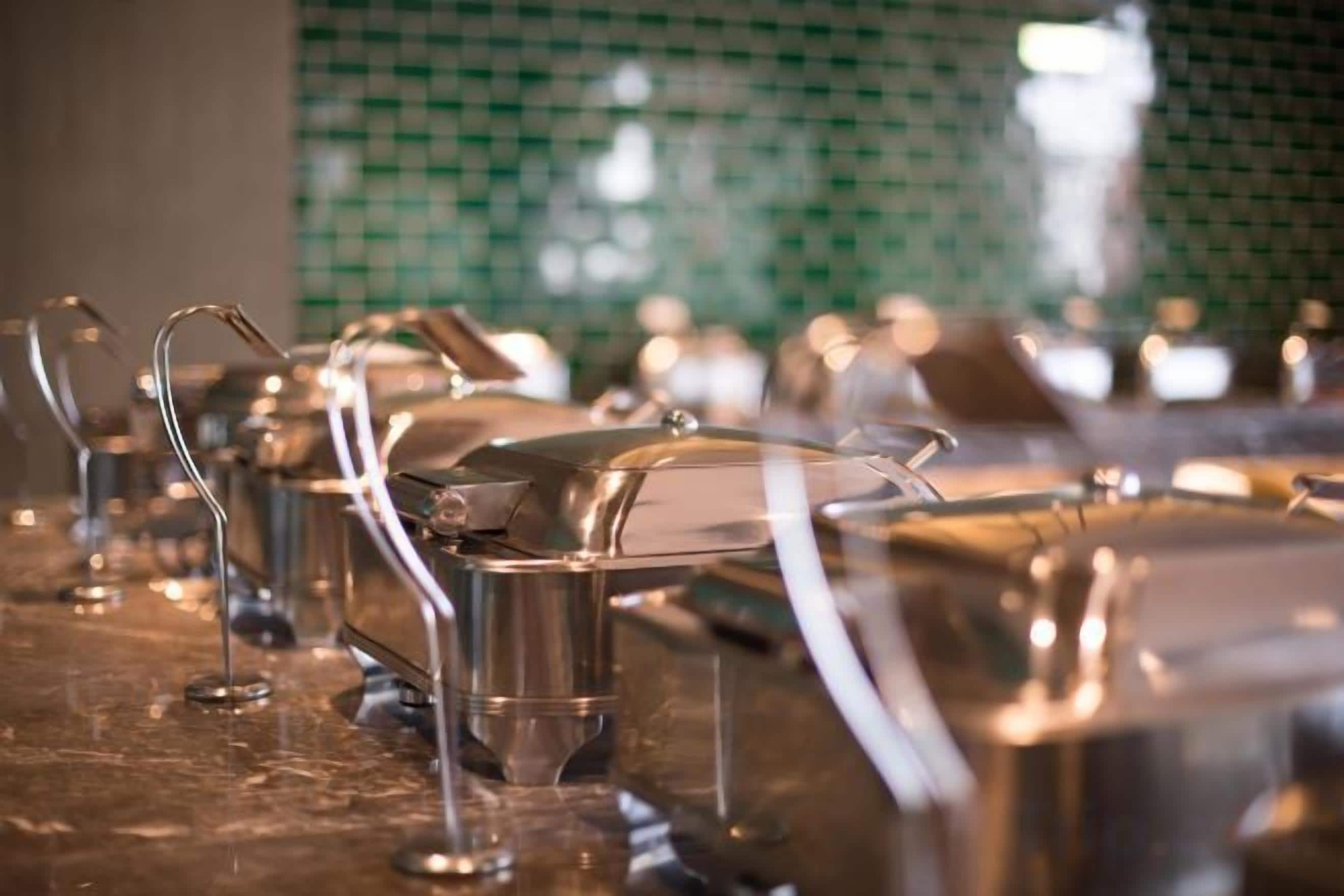 Eine Bar mit Edelstahl-Barhocker und einer grün gefliesten Rückwand.