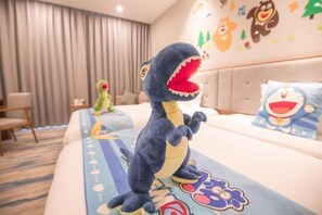 Une chambre d’hôtel avec un lit agrémenté d’un doudou en forme de dinosaure, d’un oreiller orné d’un personnage de dessin animé et d’un mur décoré d’autocollants représentant des animaux.