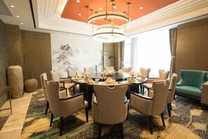A conference room with a round table, chairs, and a chandelier.
