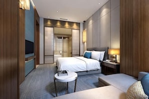 A modern hotel room with a bed, bedside table, lamp, and a TV.