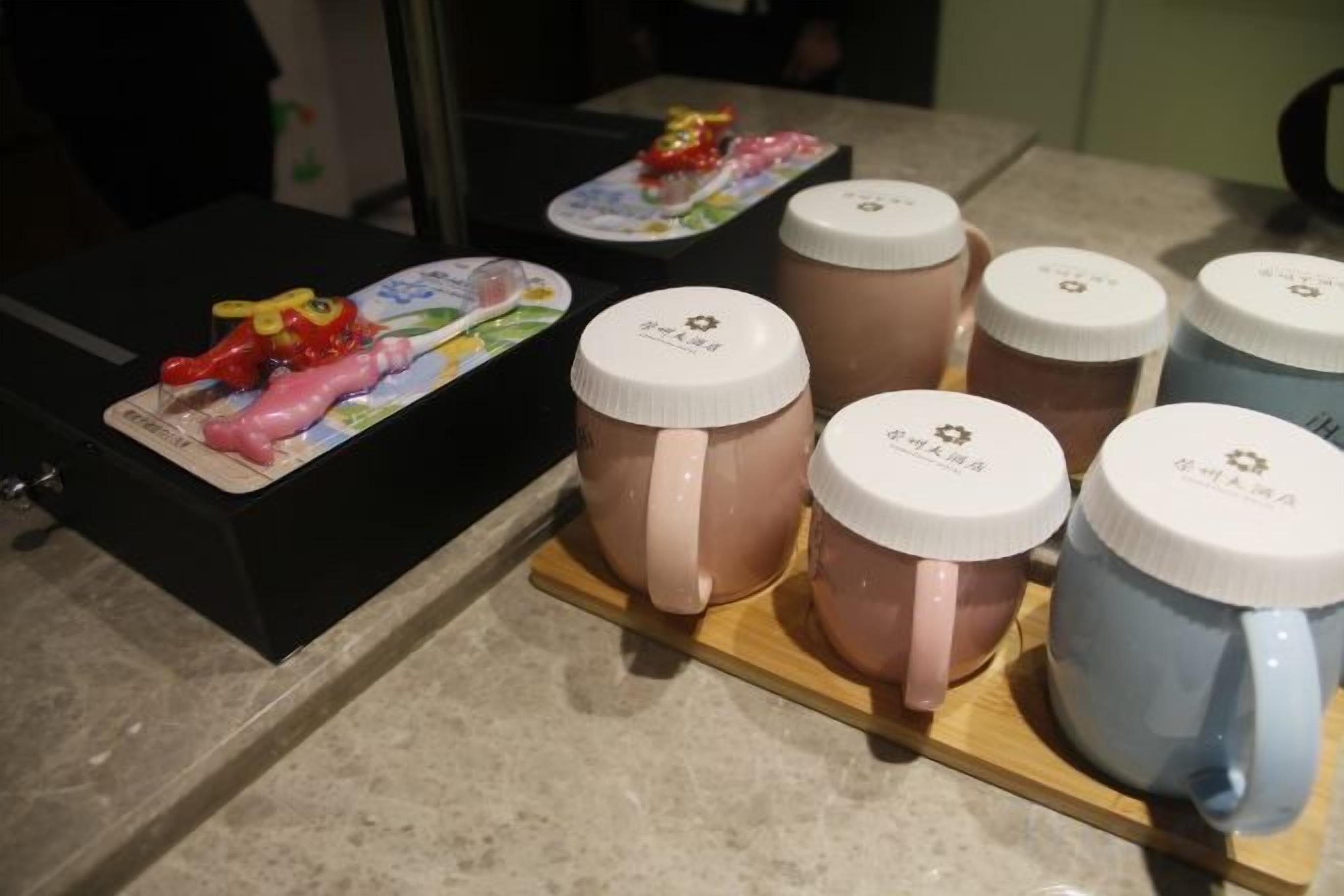 A display of ceramic mugs with lids on a wooden stand.