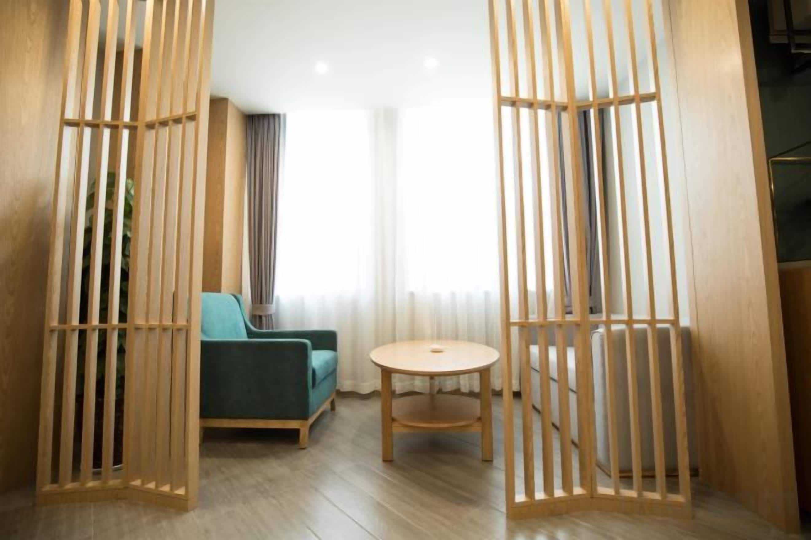 A room with a sofa, a round table, and a wooden partition.
