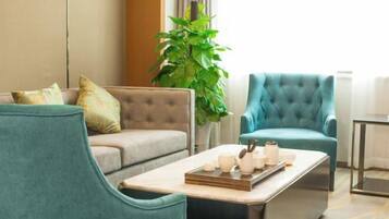 Una sala de estar moderna con un sofá, dos sillones, una mesa de centro con una bandeja de objetos y una planta verde grande.