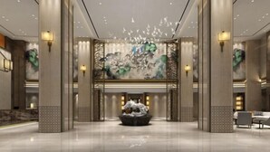 Een ruime lobby met een fontein in het midden, hoge plafonds en moderne verlichting.