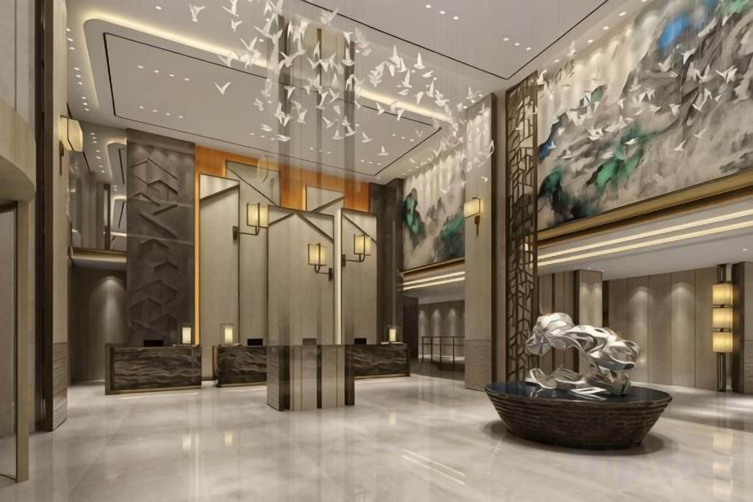 Una hall moderna con una reception, un pannello decorativo con motivi astratti e un grande quadro.