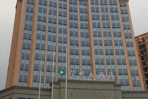 Un edificio alto con diseño moderno, que presenta una serie de ventanales verticales y una entrada destacada con un letrero.