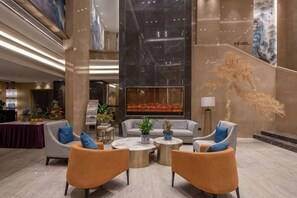 A spacious lobby with modern furnishings, a large abstract art piece, and a reception desk.