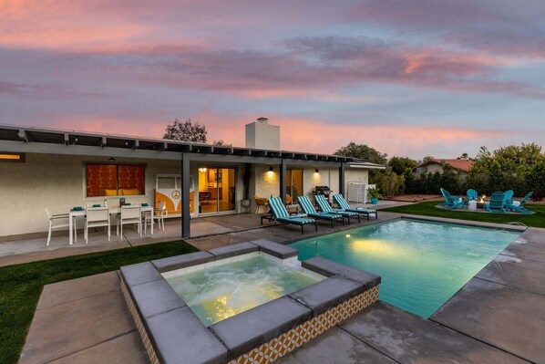 A modern house with a swimming pool, outdoor seating, and a patio area.