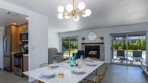 Een moderne keuken met een eethoek, een open haard en uitzicht op een zwembad.