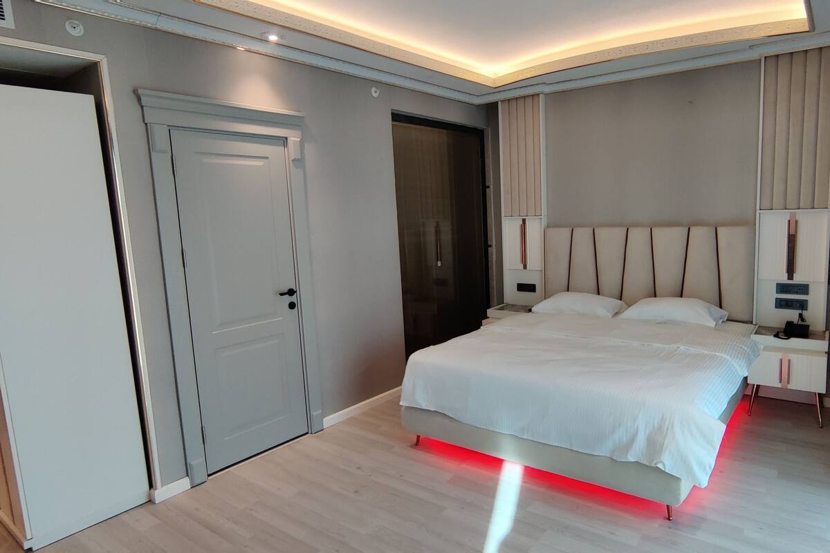 A modern bedroom with a bed, bedside tables, and a wardrobe.