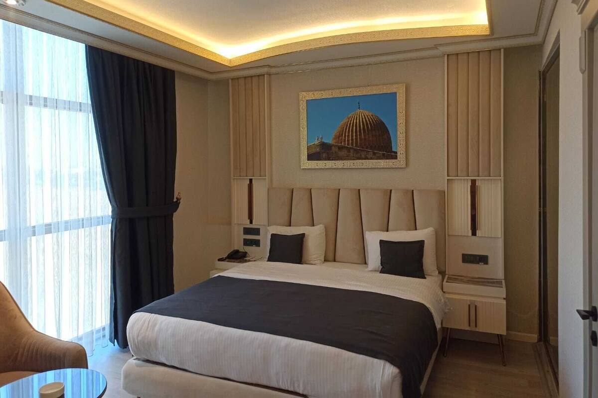 A hotel room with a large bed, bedside tables, a desk, and a chair.