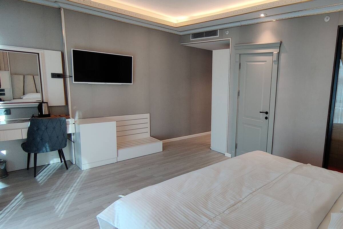 A modern hotel room with a bed, a desk, a chair, a TV, and a sliding door.