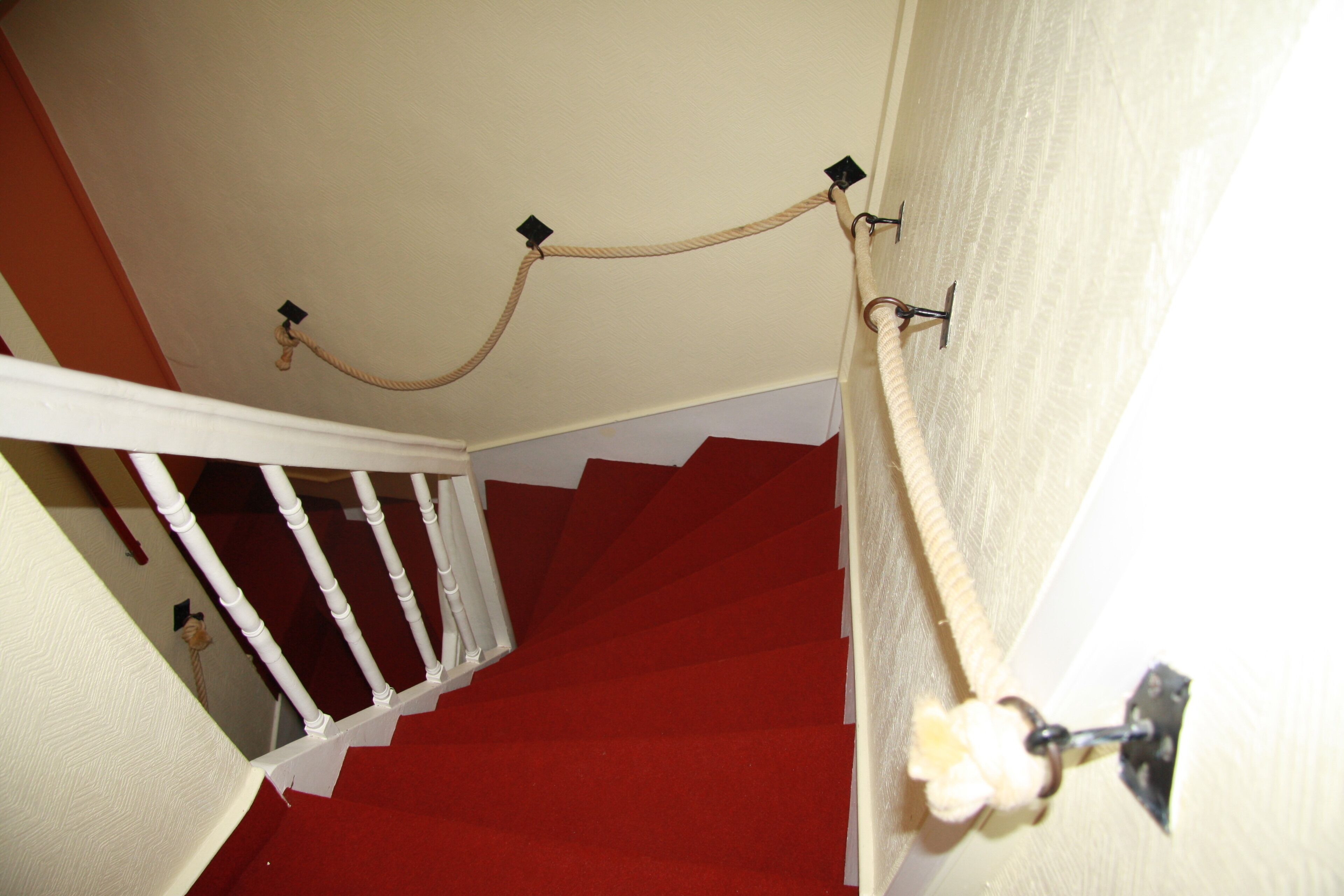Un escalier recouvert d’une moquette rouge et doté de rampes blanches.