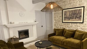 Un salon avec une cheminée, un ensemble de canapés, une table basse et un luminaire suspendu.