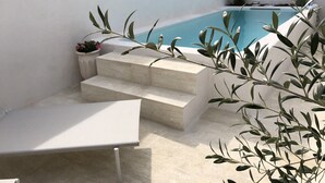 Une terrasse sur le toit avec une piscine, des marches menant à la piscine et un espace détente.