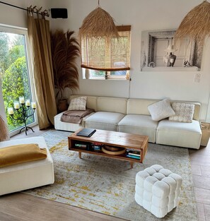 A living room with a sofa, a coffee table, a potted plant, and a hanging light fixture.