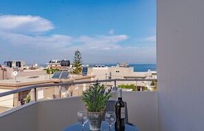 A balcony with a table set for two, a bottle of wine, and a potted plant. - Saint-Trope Studios (Chania)
