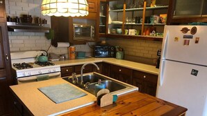 A kitchen with a wooden island, stainless steel sink, and a white refrigerator.