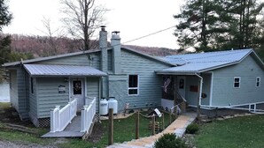 A two-story house with a porch, a small deck, and a pathway leading to the entrance.