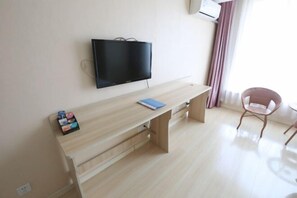 A room with a wooden desk, a flat-screen TV, a chair, and a window with curtains. - Jinshang Express Motel (Shenyang)