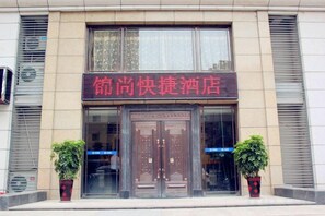 A hotel entrance with a sign in red characters, two potted plants, and a double door. - Jinshang Express Motel (Shenyang)