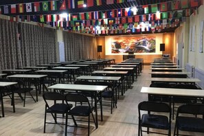 A conference room with rows of tables and chairs, a podium, and a backdrop with flags. - Jinshang Express Motel (Shenyang)