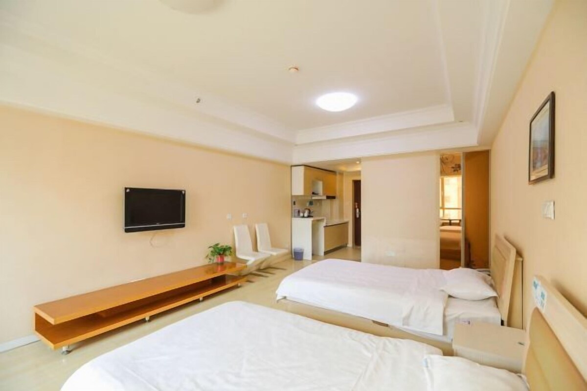 A hotel room with two beds, a TV, a desk, and a seating area.