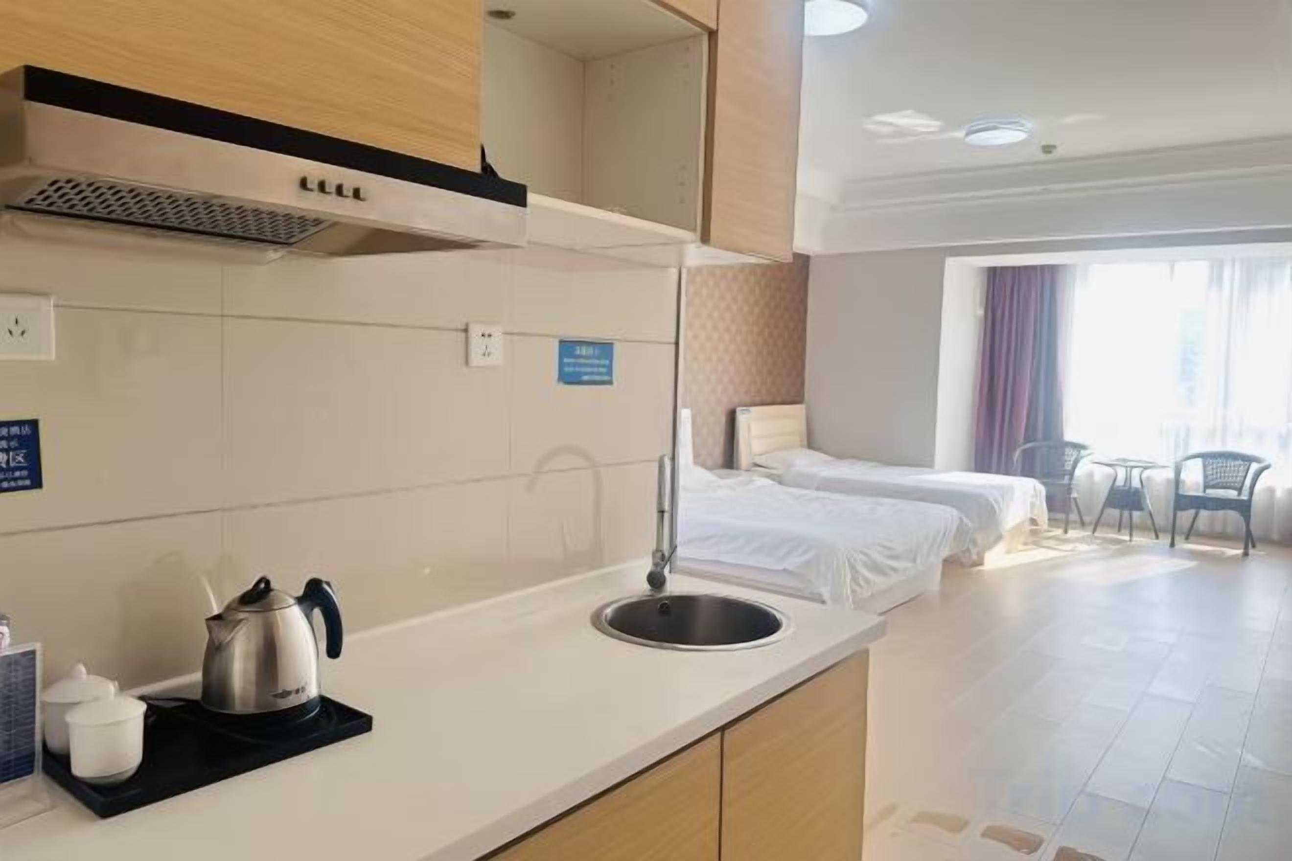 Una habitación de hotel con kitchenette, cama, baño y balcón.