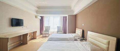A hotel room with two beds, a desk, a chair, and a television.