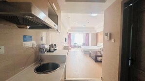 Una camera d'albergo con angolo cottura, un letto, una scrivania e vista sulla strada.