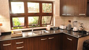 Een keuken met een groot raam, een spoelbak en diverse apparaten, waaronder een broodrooster, waterkoker en blender.