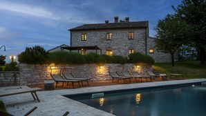 A stone building with a swimming pool, lounge chairs, and a pergola. - Checello 12 by Marche Holiday Villas (Cagli)