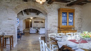 A rustic dining area with stone walls, wooden furniture, and a cabinet with glass doors. - Checello 12 by Marche Holiday Villas (Cagli)
